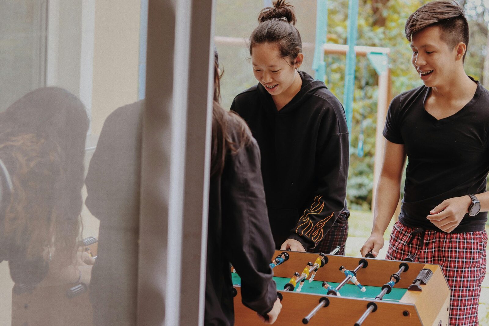Teenagers laughing together while playing table football