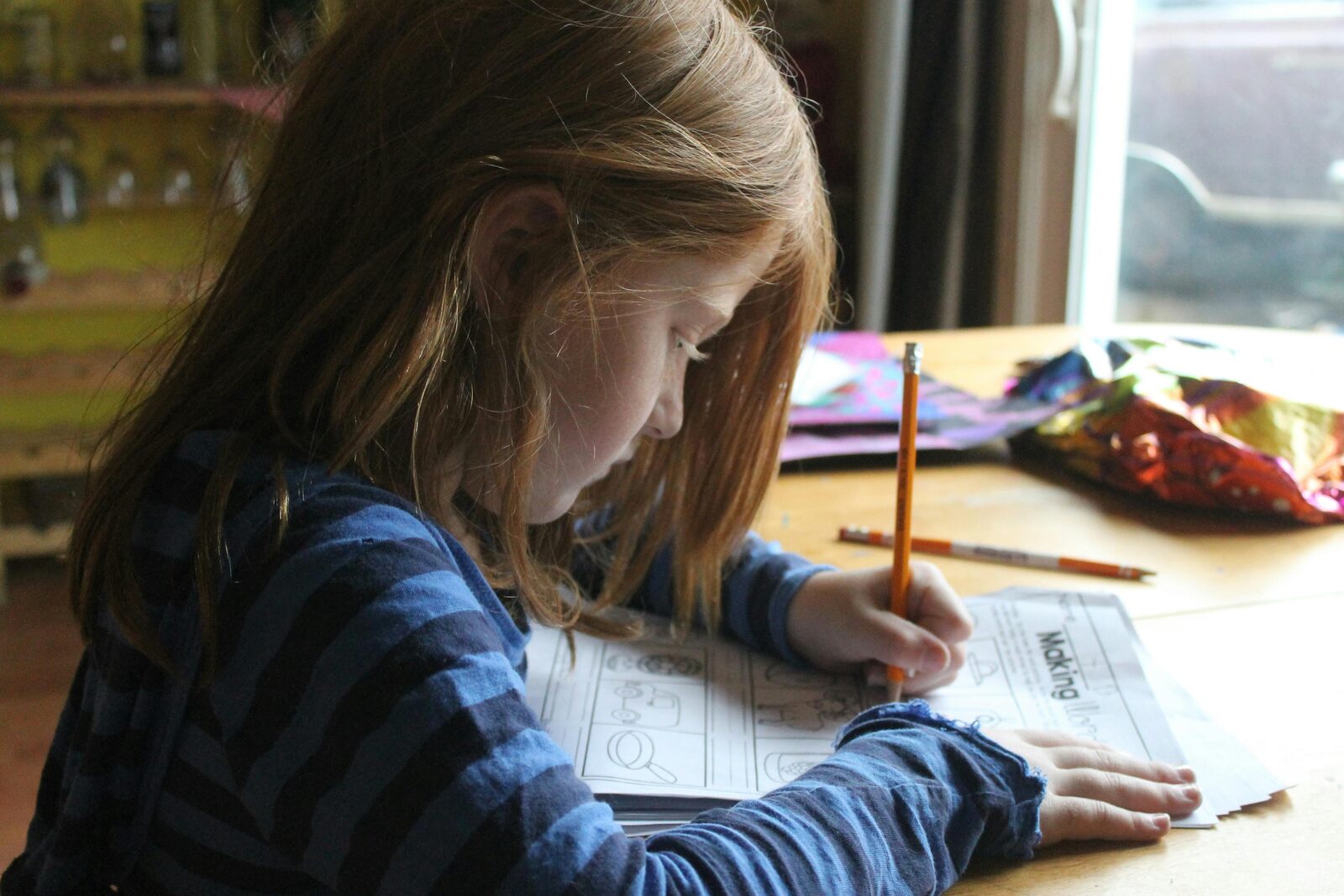 Young girl concentrating on a schoolwork worksheet at a table