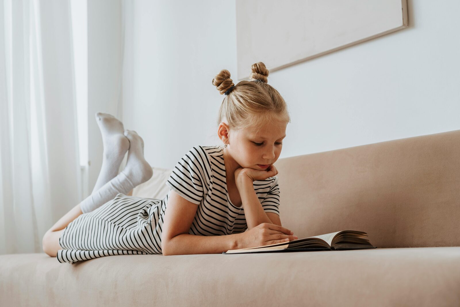 Girl lying on a sofa reading a book
