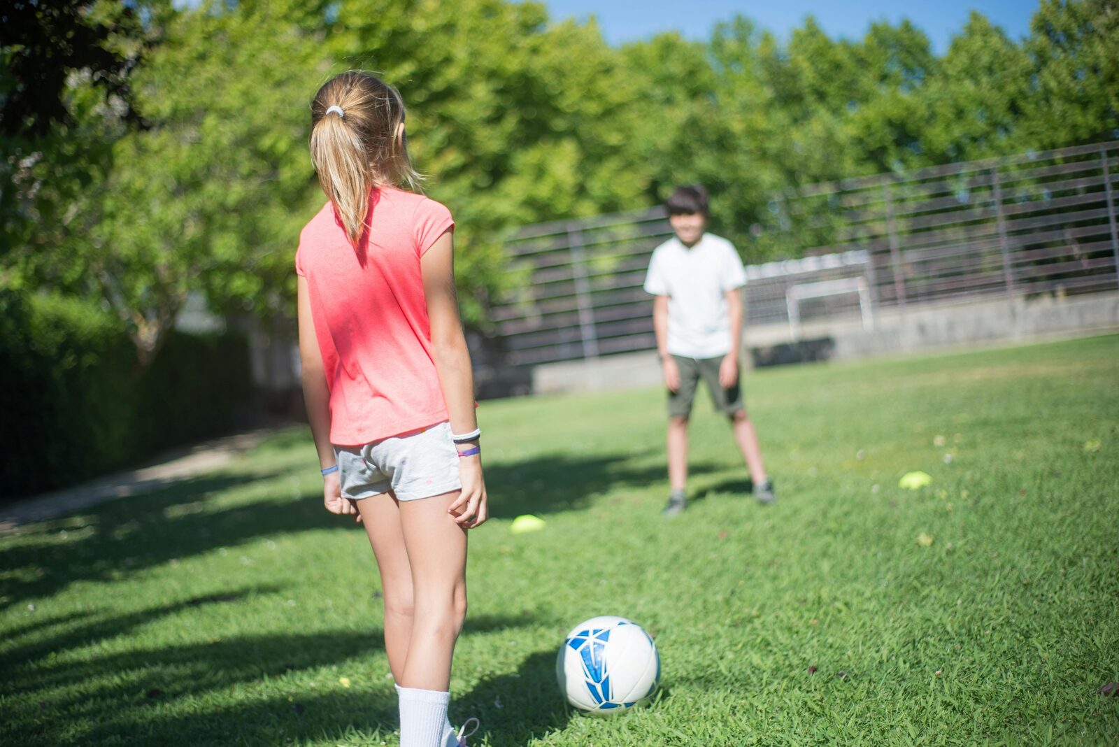 Two children playing football together in a sunny garden