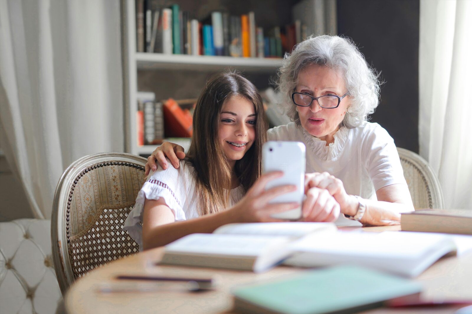 Grandmother and granddaughter smiling while looking at a phone together