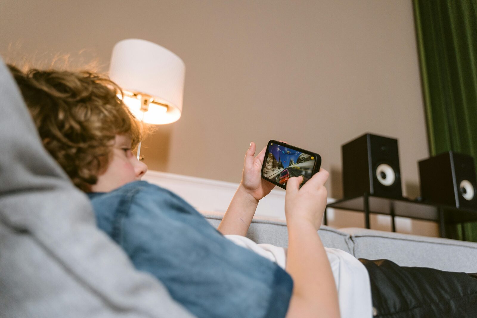 Boy absorbed in playing a game on a smartphone alone on the sofa