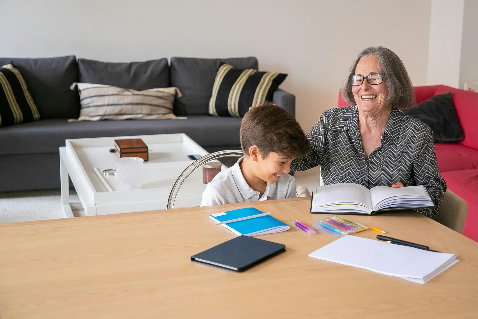 Grandmother and boy laughing together while doing homework at a table