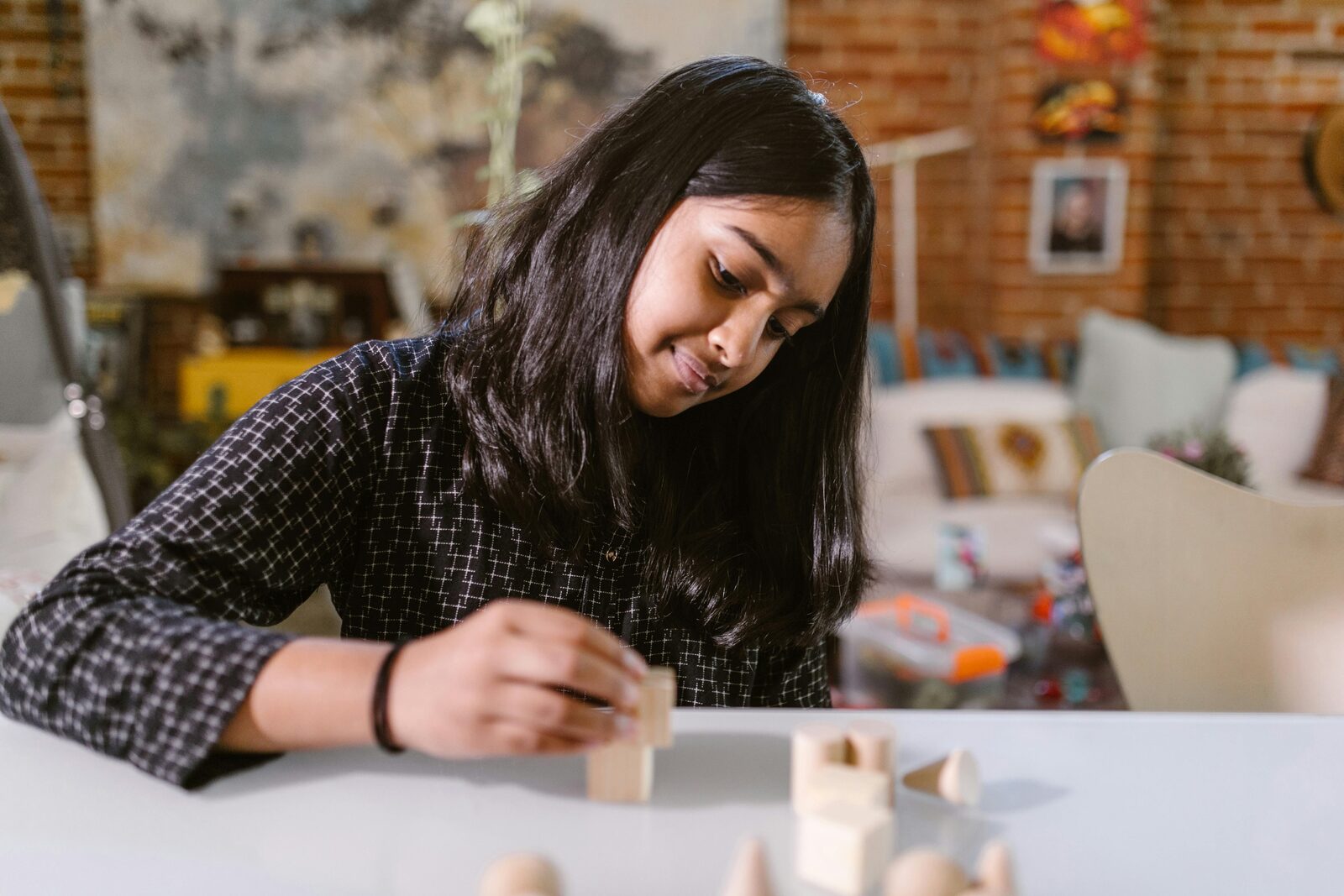Girl concentrating while building with wooden blocks at home