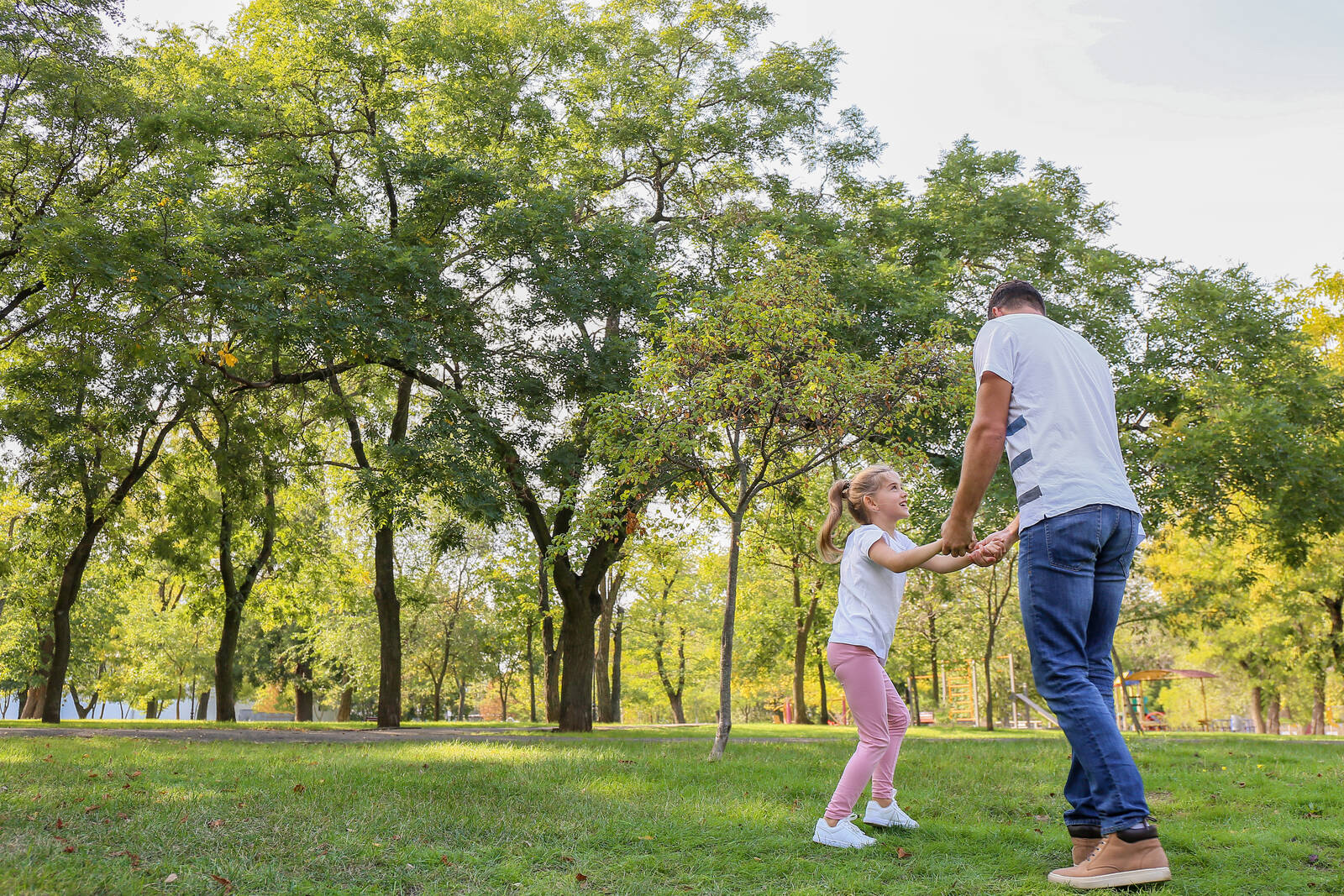 Father holding hands and playing with his daughter in a park